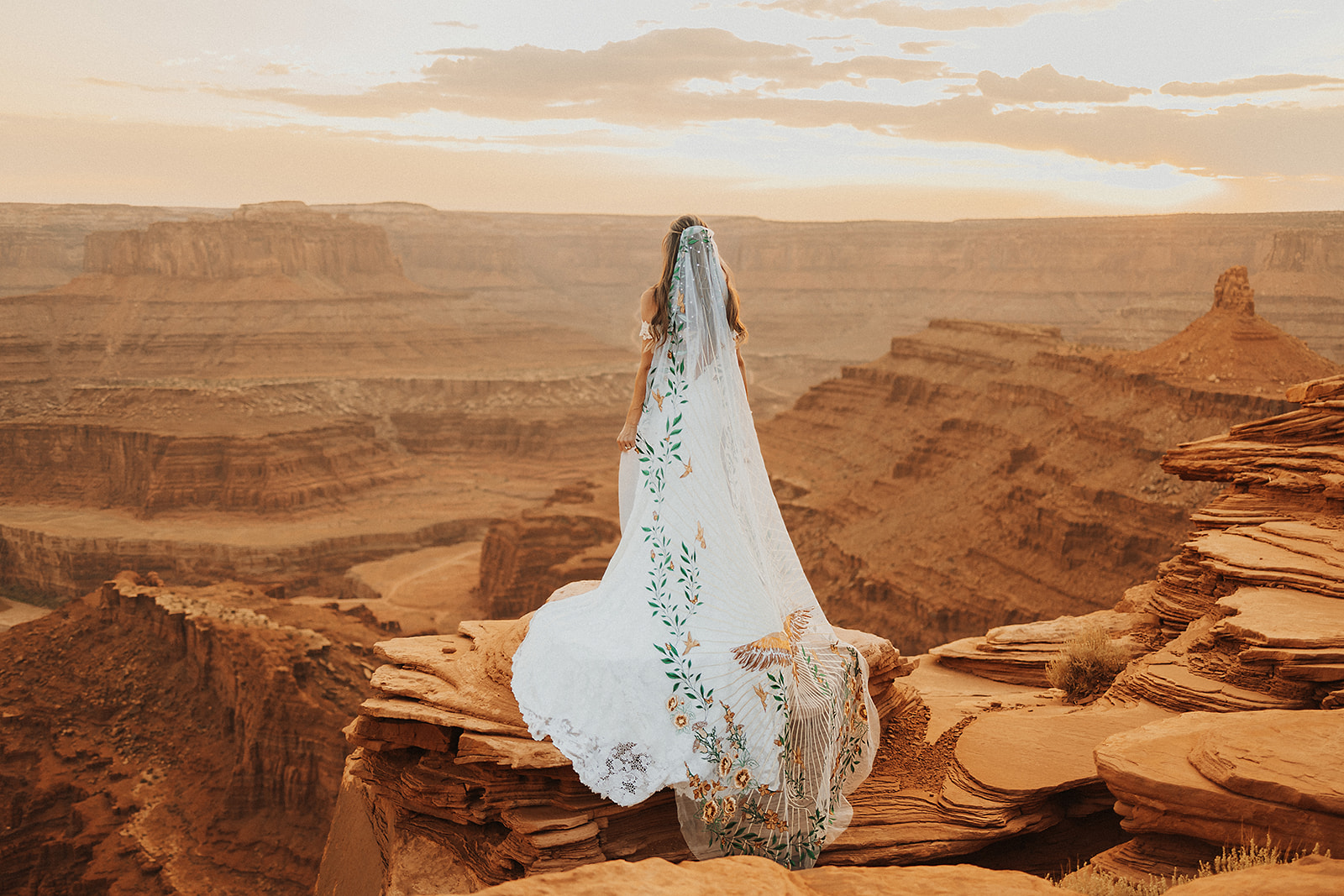 A Moab Elopement adventure with a bride standing on a red cliff